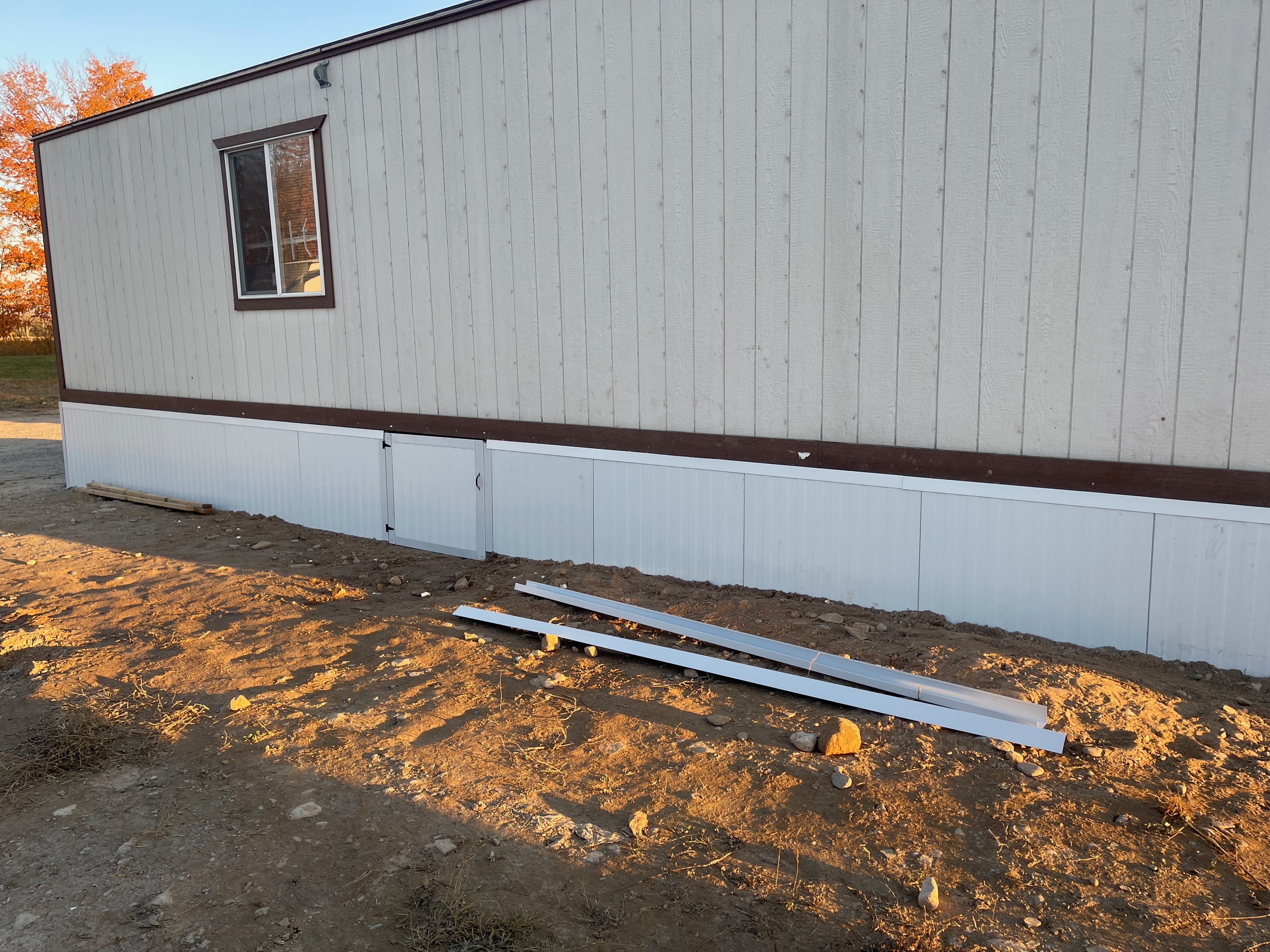 White metal trim pieces and installed skirting detail beside a panel-clad structure